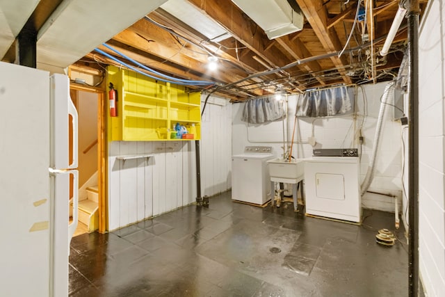 unfinished basement featuring freestanding refrigerator, washing machine and dryer, and a sink