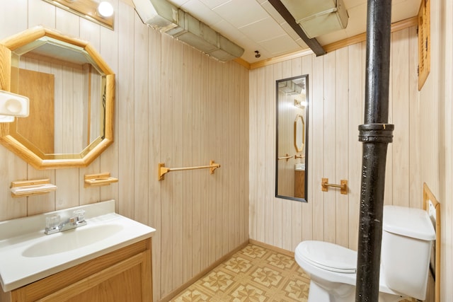 half bath featuring wood walls, vanity, toilet, and tile patterned floors