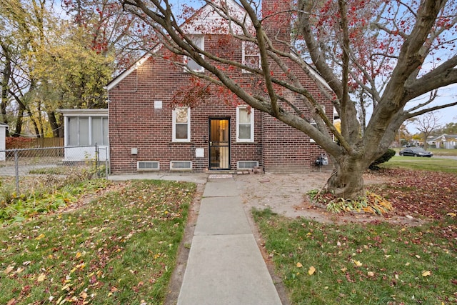 view of front of home featuring a front yard, brick siding, and fence