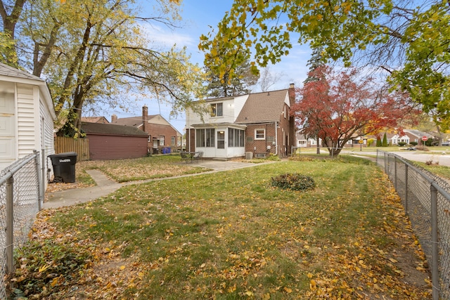 view of yard featuring an outdoor structure, a fenced backyard, and a sunroom