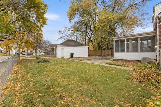 view of yard featuring an outdoor structure, a patio area, a fenced backyard, and a sunroom