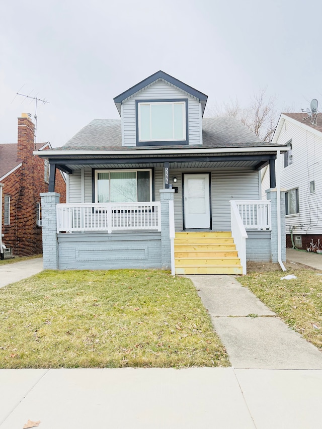 bungalow-style house with a front lawn, a porch, and roof with shingles