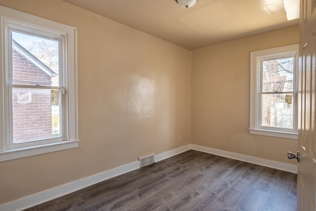 empty room featuring visible vents, baseboards, and dark wood-type flooring