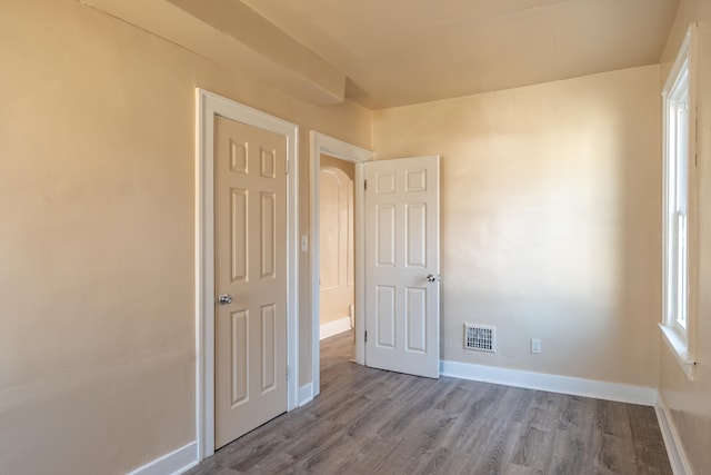 unfurnished bedroom featuring wood finished floors, visible vents, and baseboards