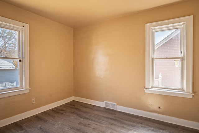 empty room featuring visible vents, baseboards, and dark wood-style flooring