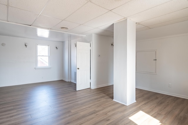 empty room with baseboards, a paneled ceiling, visible vents, and wood finished floors