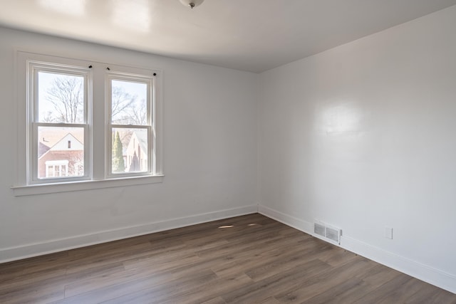 spare room with visible vents, baseboards, and dark wood-type flooring