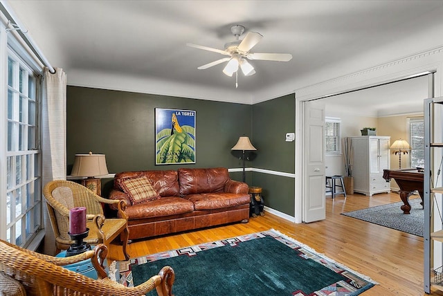 living area featuring baseboards, a ceiling fan, and wood finished floors