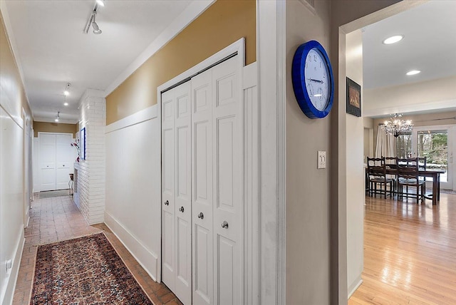 corridor featuring a chandelier, recessed lighting, baseboards, light wood-style floors, and track lighting