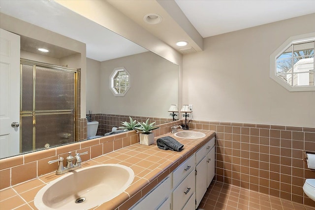 full bath with a sink, toilet, and tile walls