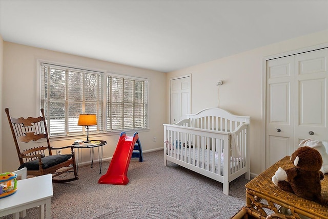 carpeted bedroom with baseboards, a crib, and multiple closets