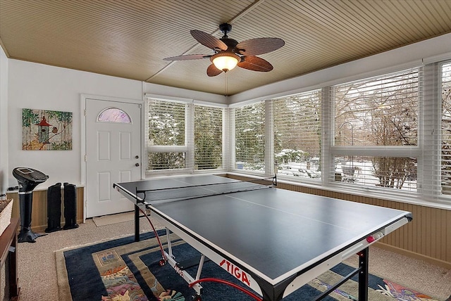 playroom featuring a ceiling fan, a wealth of natural light, light carpet, and wood walls