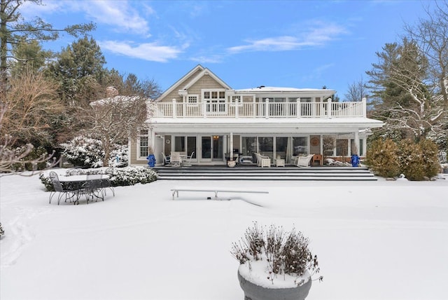 snow covered property with a balcony and outdoor dining space