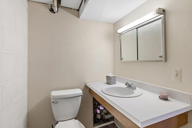 half bath with toilet, vanity, and concrete block wall