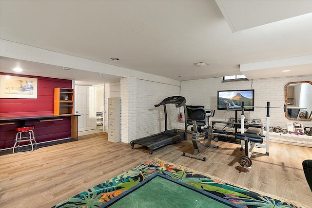 workout room with a dry bar, brick wall, and wood finished floors