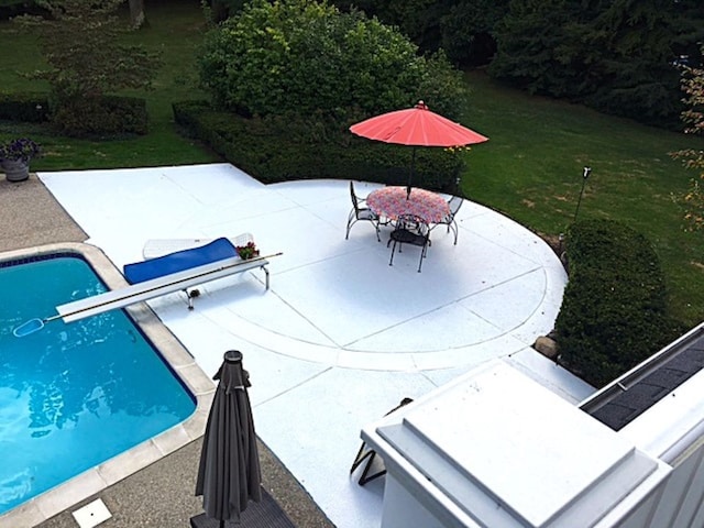 outdoor pool with outdoor dining space, a patio, and a lawn