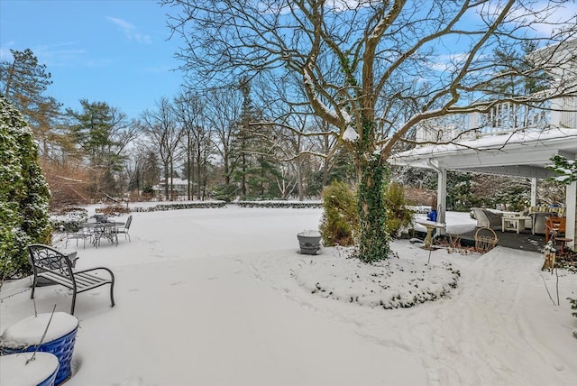 snowy yard with outdoor dining area and a patio