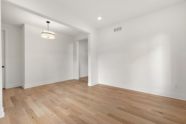 spare room with light wood-style floors, visible vents, and baseboards