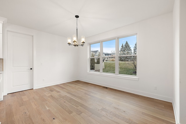 unfurnished dining area with baseboards, visible vents, a notable chandelier, and light wood finished floors