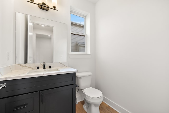 bathroom featuring baseboards, vanity, toilet, and wood finished floors