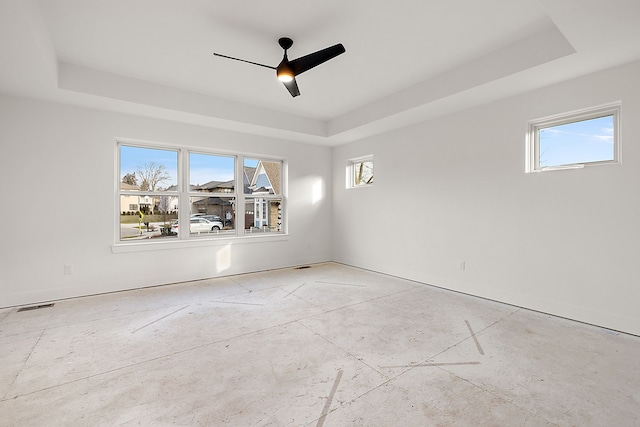 empty room featuring visible vents, a tray ceiling, and a ceiling fan