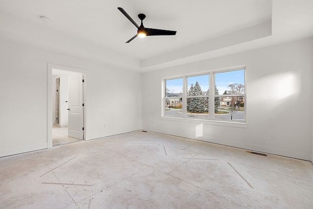 unfurnished room with visible vents, a tray ceiling, and a ceiling fan