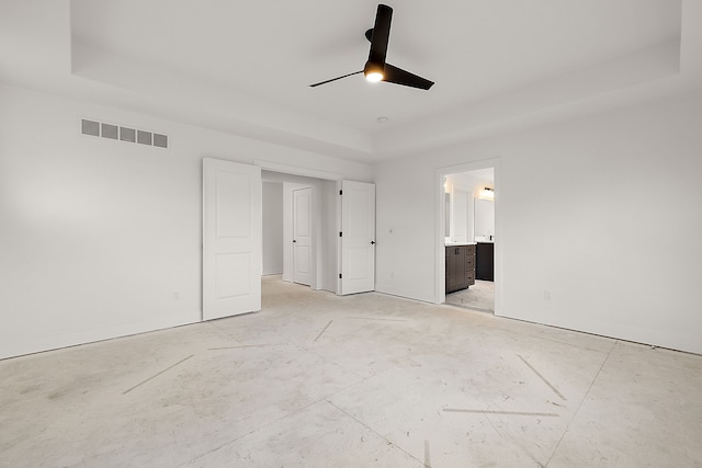 unfurnished bedroom featuring a ceiling fan, a raised ceiling, visible vents, and connected bathroom