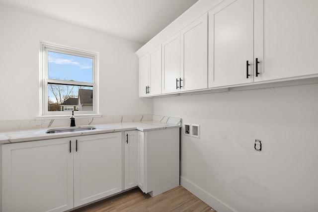 laundry room featuring washer hookup, light wood finished floors, cabinet space, a sink, and baseboards