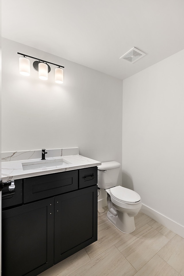 bathroom with visible vents, toilet, vanity, wood finished floors, and baseboards