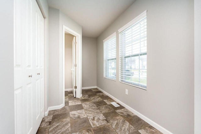 unfurnished bedroom featuring a closet, visible vents, stone finish flooring, and baseboards