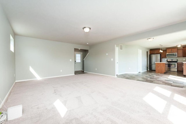 unfurnished living room featuring light carpet, visible vents, and baseboards