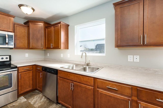 kitchen with light countertops, appliances with stainless steel finishes, brown cabinetry, and a sink