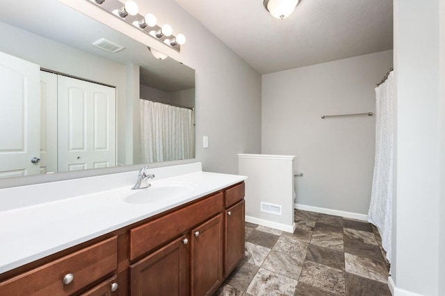 full bath with stone finish flooring, visible vents, vanity, and baseboards