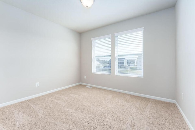 empty room with light carpet, visible vents, and baseboards