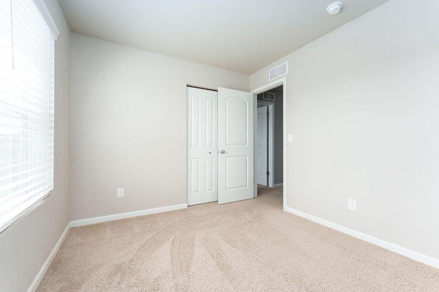 unfurnished bedroom featuring carpet, a closet, visible vents, and baseboards