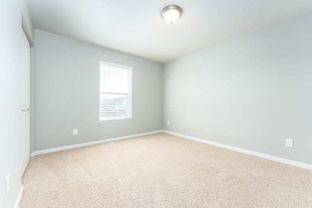 spare room with baseboards and light colored carpet