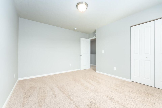 unfurnished bedroom with carpet floors, visible vents, baseboards, and a closet