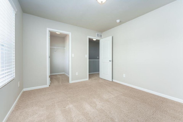 unfurnished bedroom featuring visible vents, baseboards, carpet, a spacious closet, and a closet