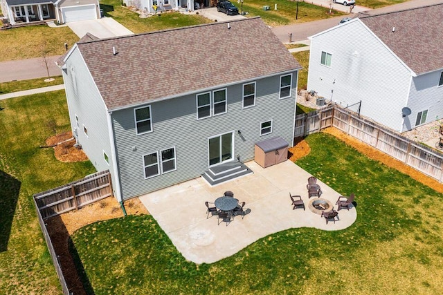 back of house featuring a patio, an outdoor fire pit, a lawn, and a fenced backyard