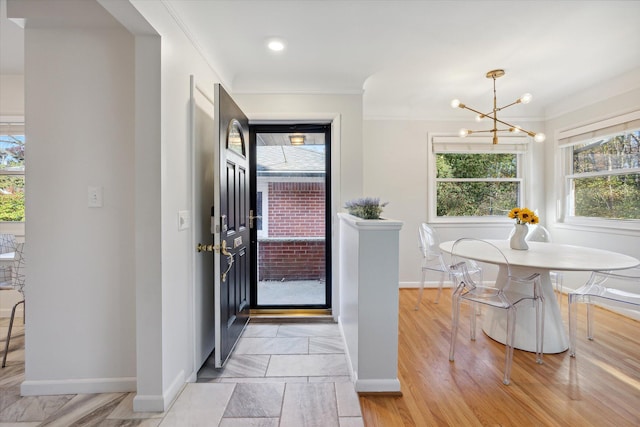 foyer entrance featuring baseboards, light wood-type flooring, an inviting chandelier, and crown molding