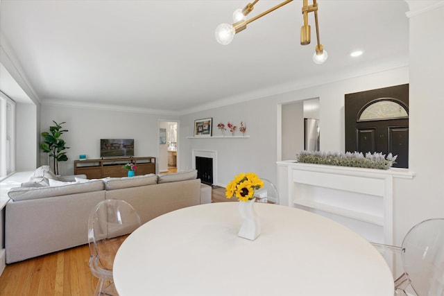 dining area with ornamental molding, a fireplace, and wood finished floors