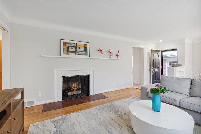 living room with a fireplace with flush hearth, wood finished floors, visible vents, and baseboards