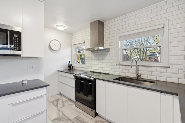 kitchen featuring dark countertops, stainless steel microwave, wall chimney range hood, a sink, and range with electric stovetop