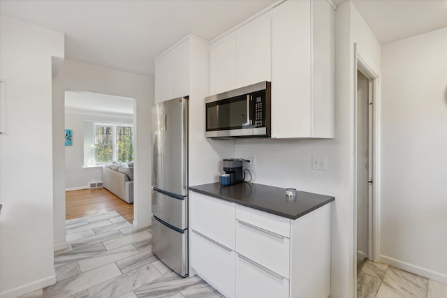 kitchen with visible vents, dark countertops, marble finish floor, stainless steel appliances, and white cabinetry