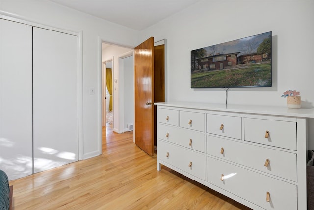 bedroom featuring light wood-style floors, baseboards, and a closet