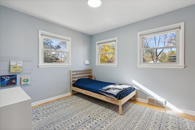 bedroom with light wood-type flooring, visible vents, and baseboards