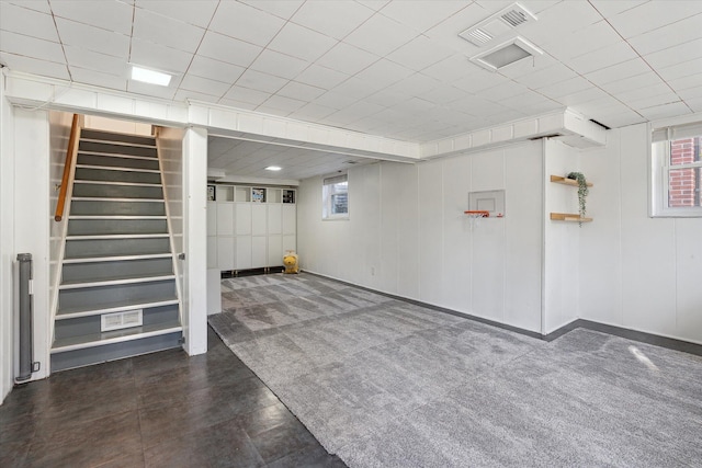 basement with carpet floors, stairs, and visible vents