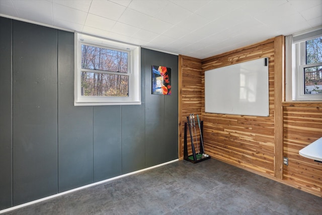 unfurnished room with wood walls and concrete floors