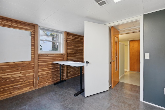 unfurnished office featuring visible vents, wood walls, and finished concrete flooring