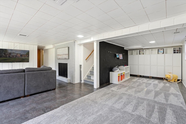 finished basement with a brick fireplace, visible vents, and stairs